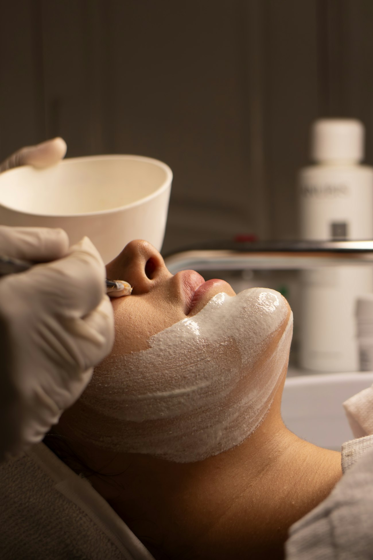 A treatment mask being applied with a brush in soft clinical light